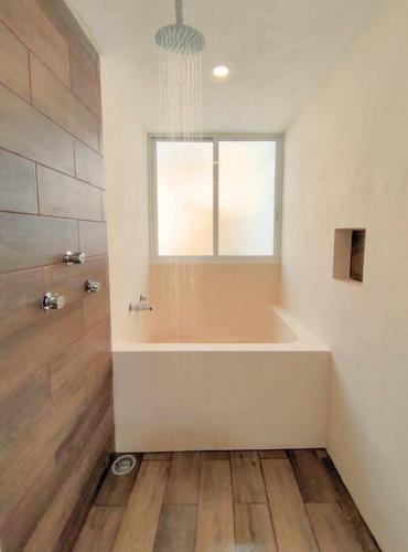 a bathroom with a bath tub and a window at Casa Colibri Central Villa with Private Pool and Tub Merida in Mérida
