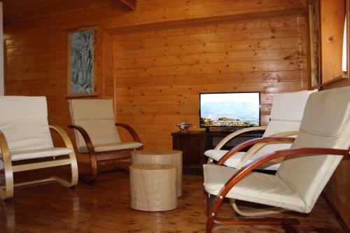 ein Wohnzimmer mit weißen Stühlen und einem TV in der Unterkunft Vacation House Home, Plitvice Lakes National Park in Plitvička Jezera