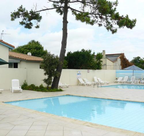 une grande piscine avec des chaises et un arbre dans l'établissement Mobilhome LA COTINIERE, à La Cotinière