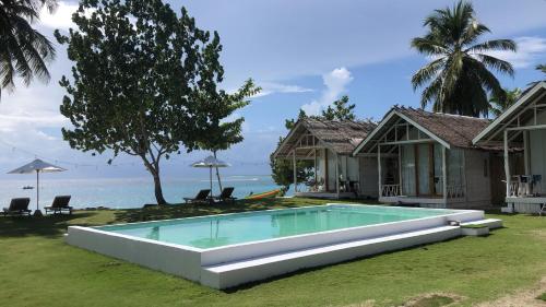 a house with a swimming pool in front of the ocean at La Belle Hollow Trees in Katiet