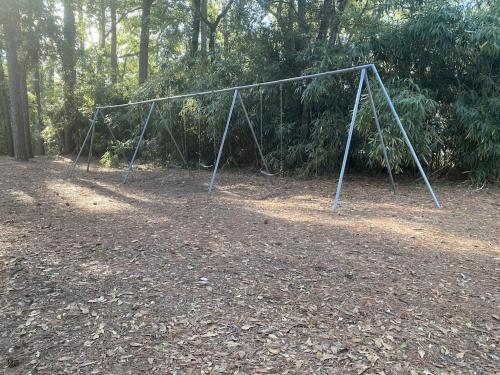 a metal swing set in a field with trees at Peaceful Relaxation and Comfort in Hilton Head Island