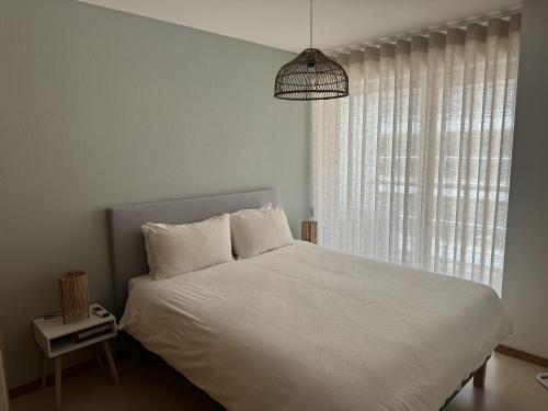 a bedroom with a white bed and a window at Apartamento Lux 1882 in Figueira da Foz