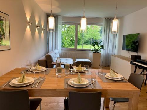 ein Esszimmer mit einem Holztisch mit Tellern und Weingläsern in der Unterkunft Leo‘s MUNICH Apartment in München