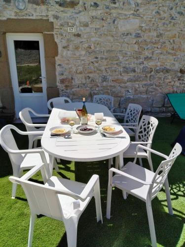 - une table et des chaises blanches avec une bouteille de vin dans l'établissement Maison de Fernand, à Montjay