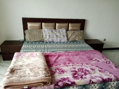 a bedroom with a large bed with a purple blanket at Murree Apartments in Murree