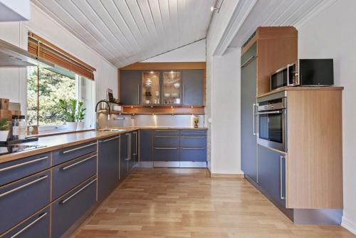 a kitchen with blue cabinets and a wooden floor at Aalesund Holiday Home 5 Bedroom! in Ålesund