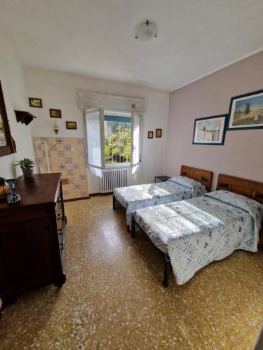 een slaapkamer met 2 bedden, een bureau en een raam bij Casa rosario e annamaria in Torri del Benaco