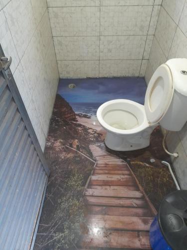a bathroom with a toilet with a painting on the floor at Área de lazer chacara in Ribeirão Preto