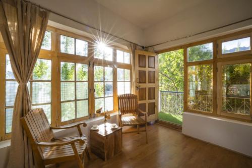 a living room with windows and a table and chairs at Rainbow Hostelier in Leh
