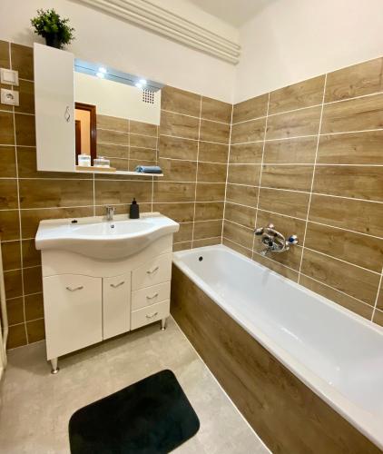 a bathroom with a tub and a sink and a bath tub at Vamos Apartman in Bük