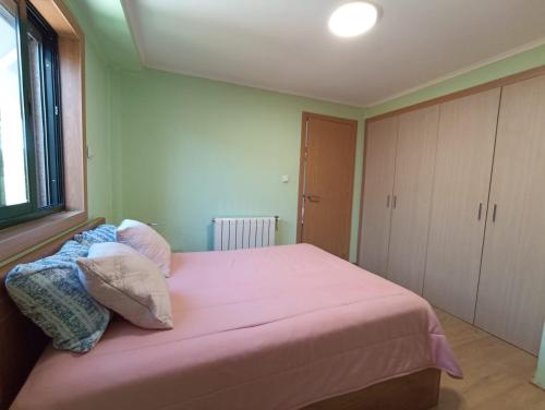 1 dormitorio con cama rosa y ventana en Mini Apartamento de 30 mts en Chaves, en Chaves