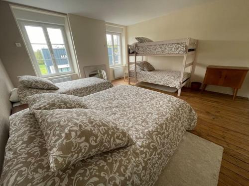 een slaapkamer met 2 bedden, een plank en ramen bij -Les Petites Planches- Gîte Familial entre Terre & Mer in La Haye-Pesnel