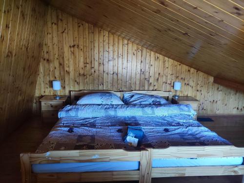a bed in a room with a wooden wall at Areál Bobo 