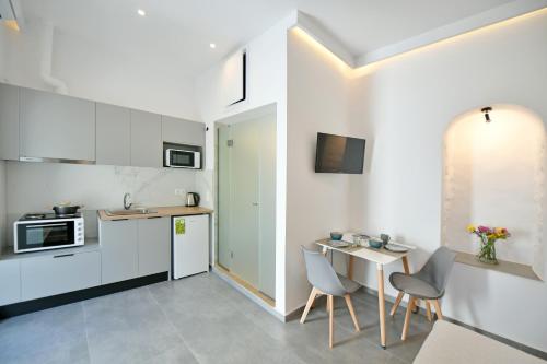 Una cocina con gabinetes blancos y una mesa y sillas. en Douskos Citrus Apartments, en Hydra