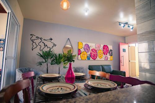 uma mesa de jantar com pratos e um vaso rosa em Casa Areal, 1 Suíte, 2 quartos, piscina garagem para 2 carros em Pelotas