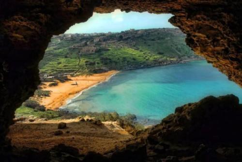 a view of a beach from a cave at Sunset Court Self Catering Sea View Apartment in Għajnsielem