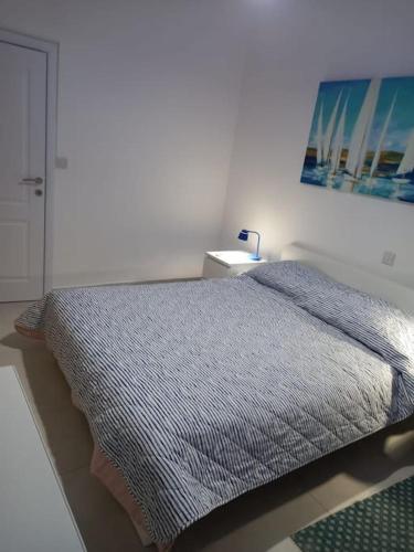 a bedroom with a bed and a painting on the wall at Sunset Court Self Catering Sea View Apartment in Għajnsielem