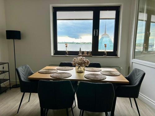 Una mesa de comedor y sillas con vista al agua. en Gemütliche Ferienwohnung im Stadtzentrum mit wundervollem Blick, en Bremerhaven