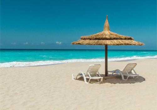 two chairs and an umbrella on the beach at Blumar Sidi Abdel Rahman 2 bedrooms Chalet North Coast in El Alamein