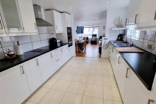 una grande cucina con armadi bianchi e ripiani neri di Causeway97 Townhouse a Portrush