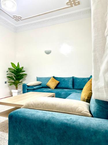 a living room with a blue couch and a table at Jolie Appt à skhirat 5min de la plage par voiture in Skhirat