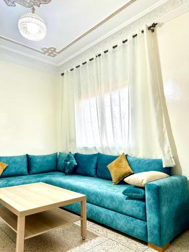 un divano blu in soggiorno con finestra di Jolie Appt à skhirat 5min de la plage a Skhirat