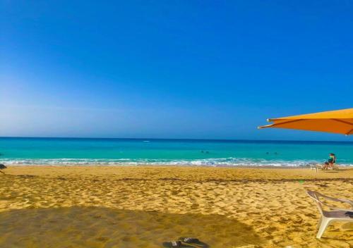 a beach with a chair and an umbrella and the ocean at Blumar Sidi Abdel Rahman 2 bedrooms Chalet North Coast in El Alamein
