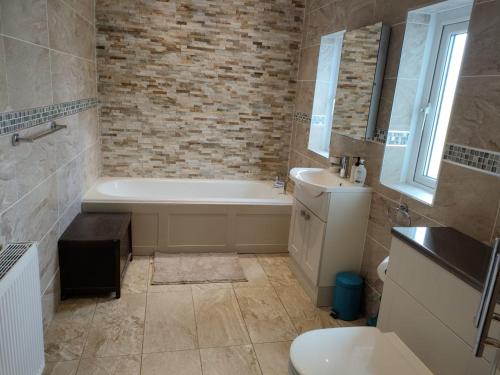 uma casa de banho com uma banheira, um WC e um lavatório. em The Summit em Kidderminster