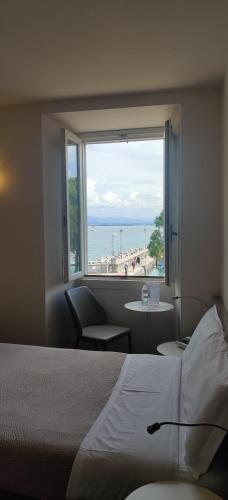 a bedroom with a view of the beach from a window at Hotel Vittorio in Desenzano del Garda