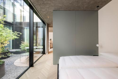 a bedroom with a white bed and glass walls at Mynt Merano Rooms in Merano