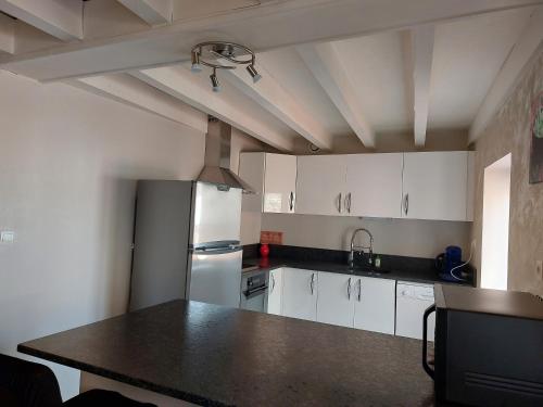 une cuisine avec des armoires blanches et un comptoir noir dans l'établissement Appartement à 2 pas du centre ville 6 personnes, 3 chambres, au Puy-en-Velay