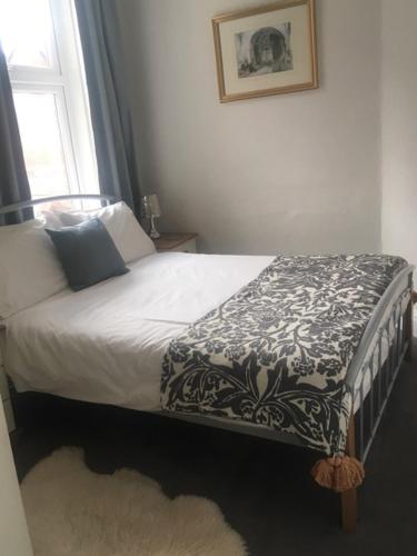 a bed with a black and white blanket and a window at Woodlands Holiday Apartments in Lytham St Annes
