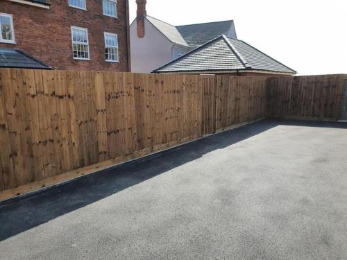 a wooden fence in front of a house at 3-Bedroom Luxury Stay With FREE Parking in Market Harborough