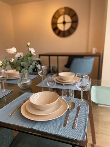 a table with plates and wine glasses and a clock at 3-Bedroom Luxury Stay With FREE Parking in Market Harborough