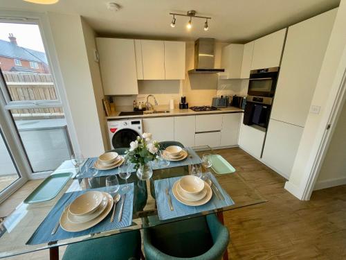 a kitchen with a dining room table with plates and bowls at 3-Bedroom Luxury Stay With FREE Parking in Market Harborough