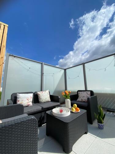 d'une terrasse avec des chaises et des tables en osier sur un balcon. dans l'établissement Triplex neuf avec toit-terrasse au pied du Métro - 10min PARIS EXPO - 4 rooms 6 beds, à Bagneux