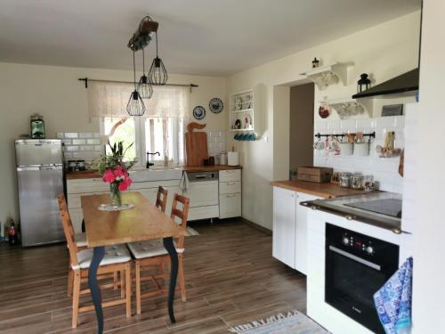 a kitchen with white cabinets and a wooden table and chairs at Dom w Siedlisku pod Orzechem in Przyłęk