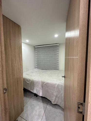 een kleine slaapkamer met een bed en een raam bij Apartamento en Bogotá en primavera in Bogota