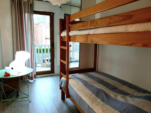 a bedroom with two bunk beds and a table and a window at Plazza front de Mer in Villers-sur-Mer