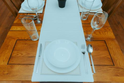 a table with a white plate and wine glasses at Detached 4 Bed - Pool Table-Patio-BBQ-Table Tennis in Quinton
