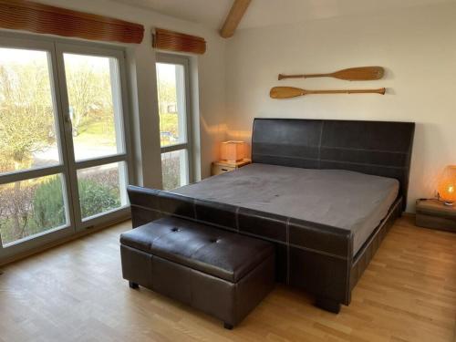 um quarto com uma cama grande e um repousa-pés de couro em Luxury holiday home with sauna em Heiligendamm