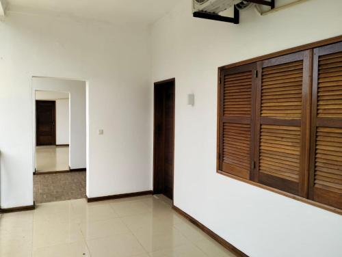 Habitación con paredes blancas y puertas de madera. en Moradia Turistica MJ ROOMS CITY, en São Tomé