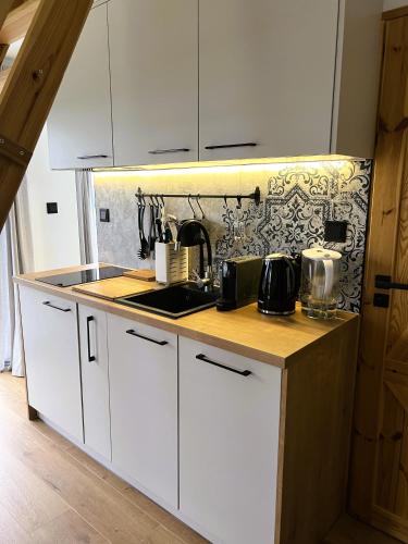 a kitchen with white cabinets and a counter top at Czarne Ptaszki in Szlembark