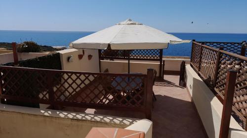 a patio with an umbrella and the ocean at Casa vacanze con terrazza panoramica vista mare in Portu Maga