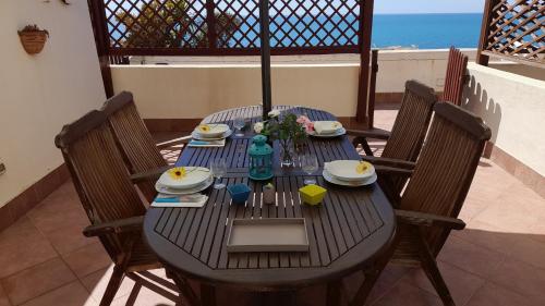 a black table with plates and flowers on a patio at Casa vacanze con terrazza panoramica vista mare in Portu Maga