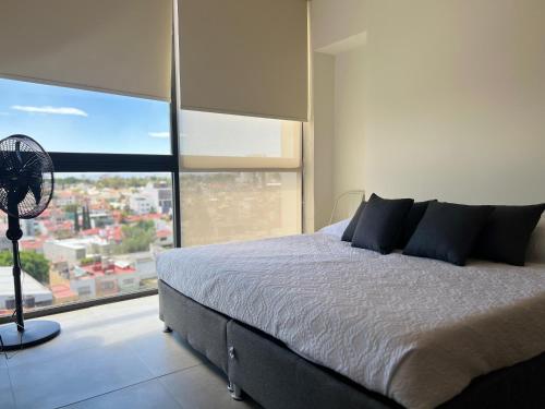 1 dormitorio con cama y ventana grande en Acogedor Departamento 2 Habitaciones, Alberca, Gym, en Guadalajara