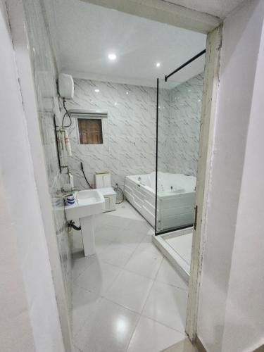 a bathroom with a tub and a sink and a toilet at Cozy Residence Abuja in Abuja
