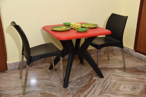 een rode tafel met twee stoelen en een bord eten erop bij HOTEL SONAR BANGLA RESORT AND DHABA in Salt Lake City