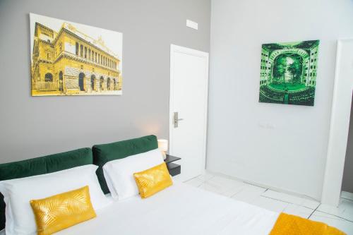 ein weißes Zimmer mit einem Bett mit gelben und weißen Kissen in der Unterkunft Palazzo Goyze in Neapel