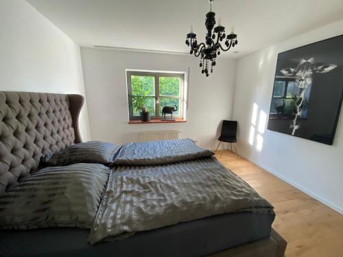 Un dormitorio con una cama grande y una lámpara de araña. en Wohnen in Weinbergsnähe en Würzburg